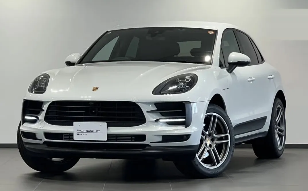 ショールームに展示された白のマカンを斜め前から撮った写真。ナンバープレートの位置に PORSCHE APPROVED のプレートが付いている