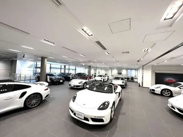 2階の展示スペース。白を中心としたポルシェが十数台並んでいる明るい屋内フロア